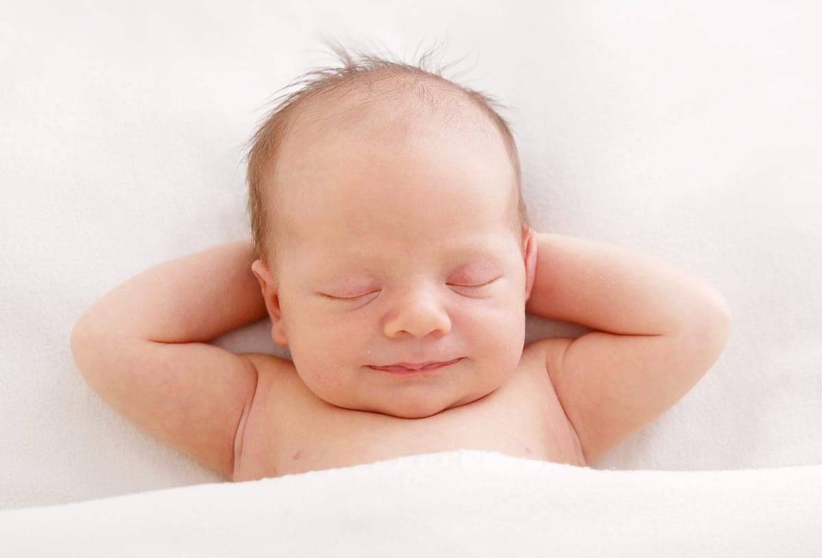 Photograph of sleeping newborn baby with blissfully relaxed expression on his face