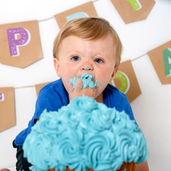 Baby boy portrait of cake smash photo session stuffing cake into mouth