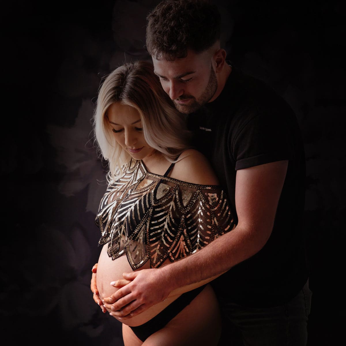 Maternity portrait of embracing couple and baby bump