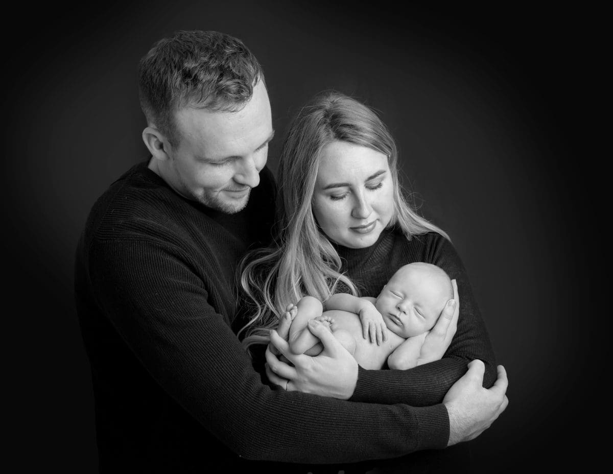 Black and white shot of couple with their new baby in an intimate family portrait photoshoot