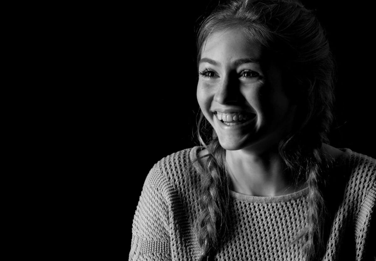 Low key portrait photograph of smiling teenager from a professional studio session